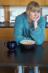 Unhappy woman sitting at breakfast table